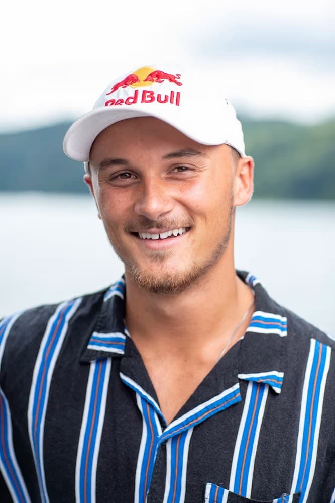 Cory Teunissen smiling in a Red Bull cap by the water